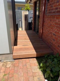 Timber deck walkway beside brick wall